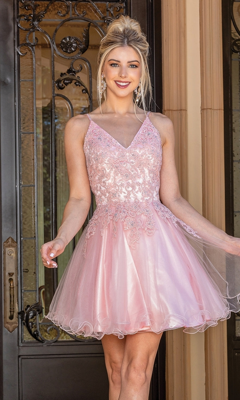 A woman smiles at the camera in front of ornate doors, wearing the Lace-Up Short Babydoll Homecoming Dress 3303—a sleeveless, light pink lace and tulle dress.